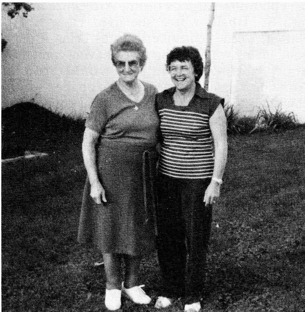 Black and white photograph of two women standing outdoors in a grassy area