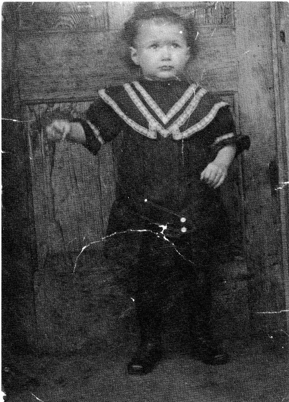 Black and white photograph of a young boy standing outdoors