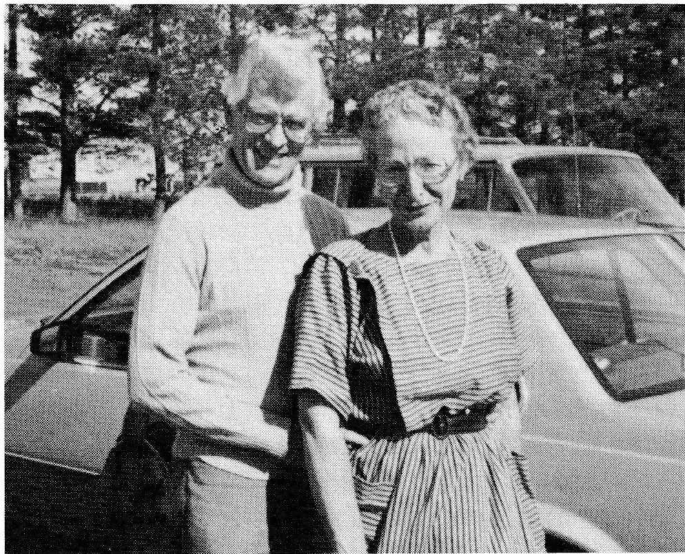 Mae and Bernard standing outdoors next to a car