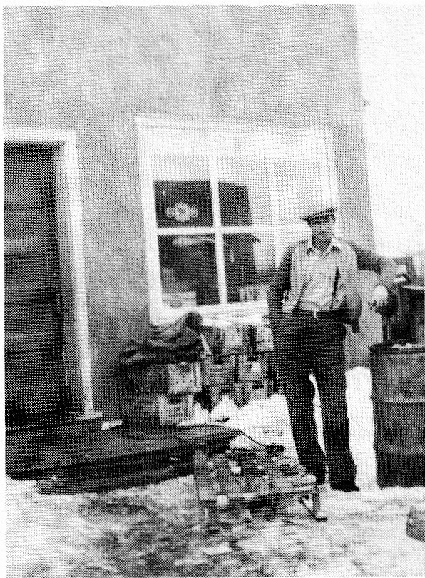 Smokey Alain standing in front of a wooden store building